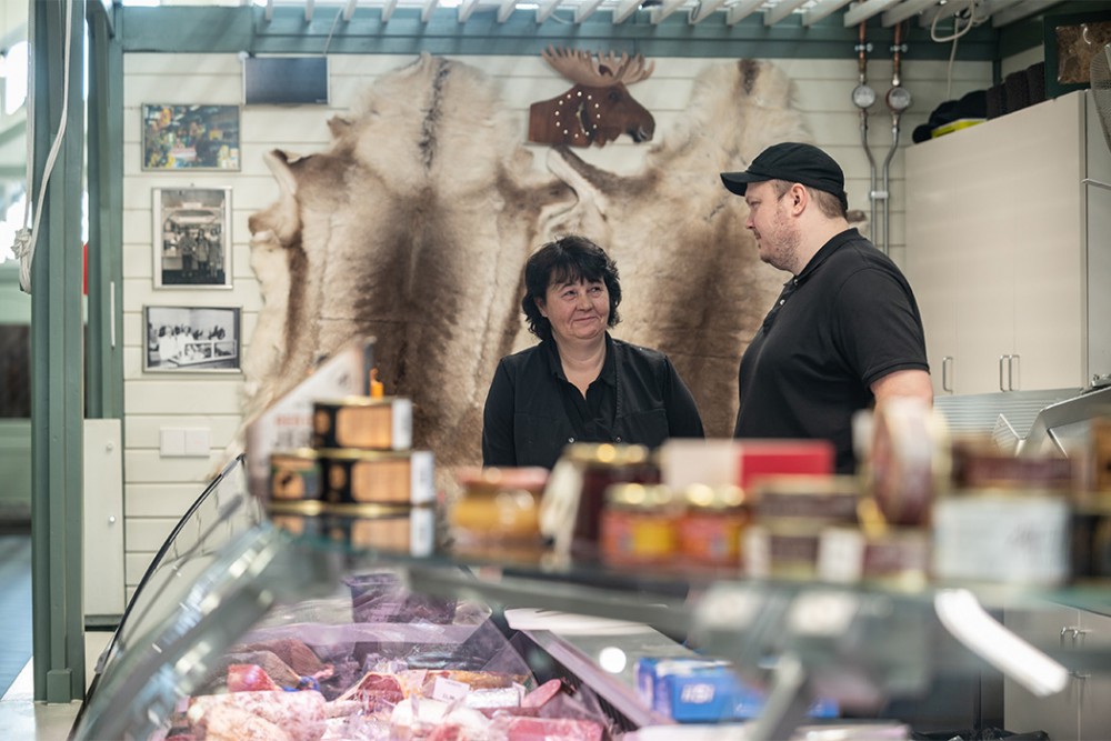 Kauppiaat juttelevat myyntitiskin takana